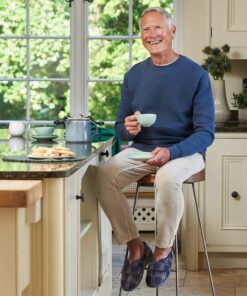 Man sitting at breakfast bar drinking coffee wearing Cosyfeet Ronnie mens slipper in Navy Highland